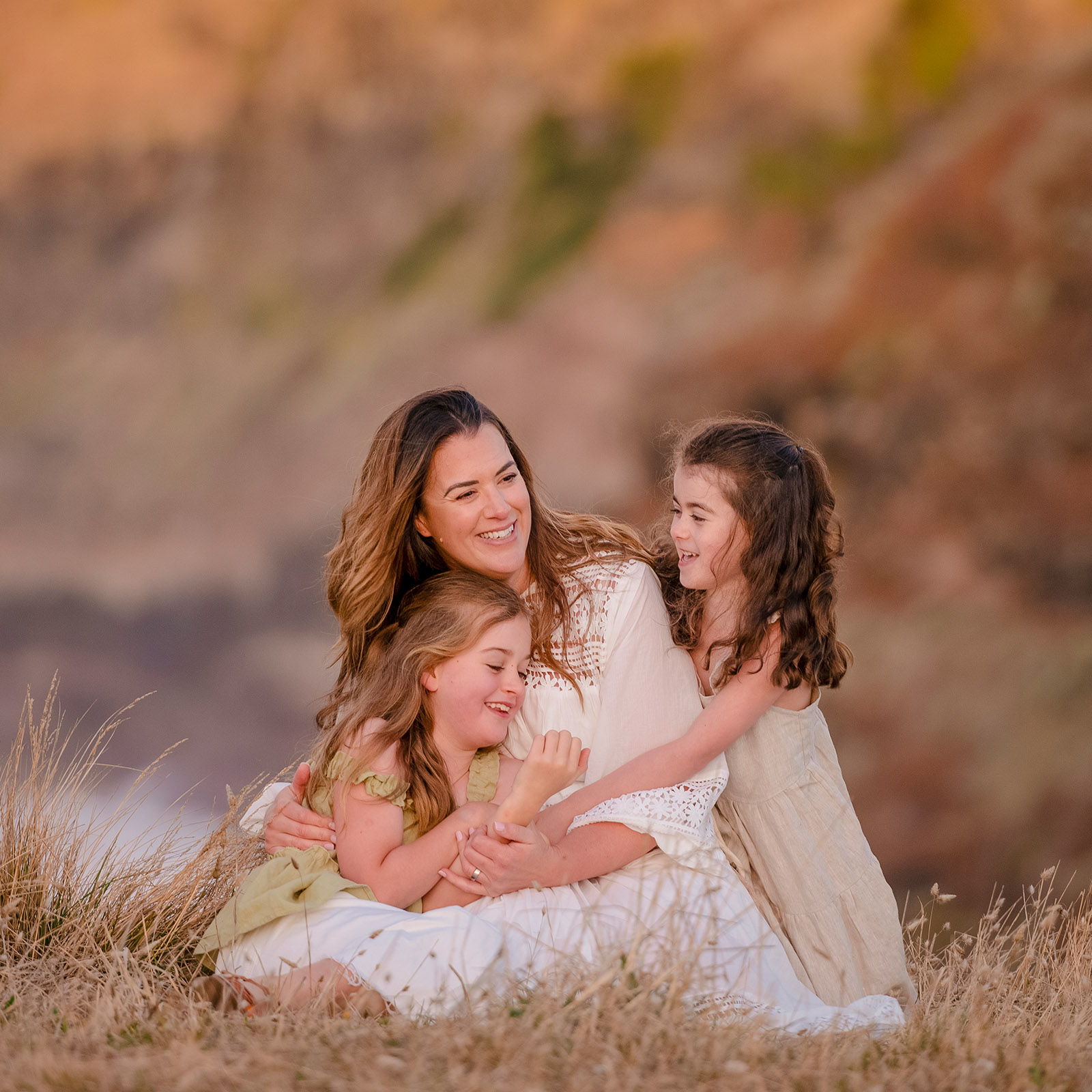 Kelly Jordan laughing with her daughters during an outdoor family portrait